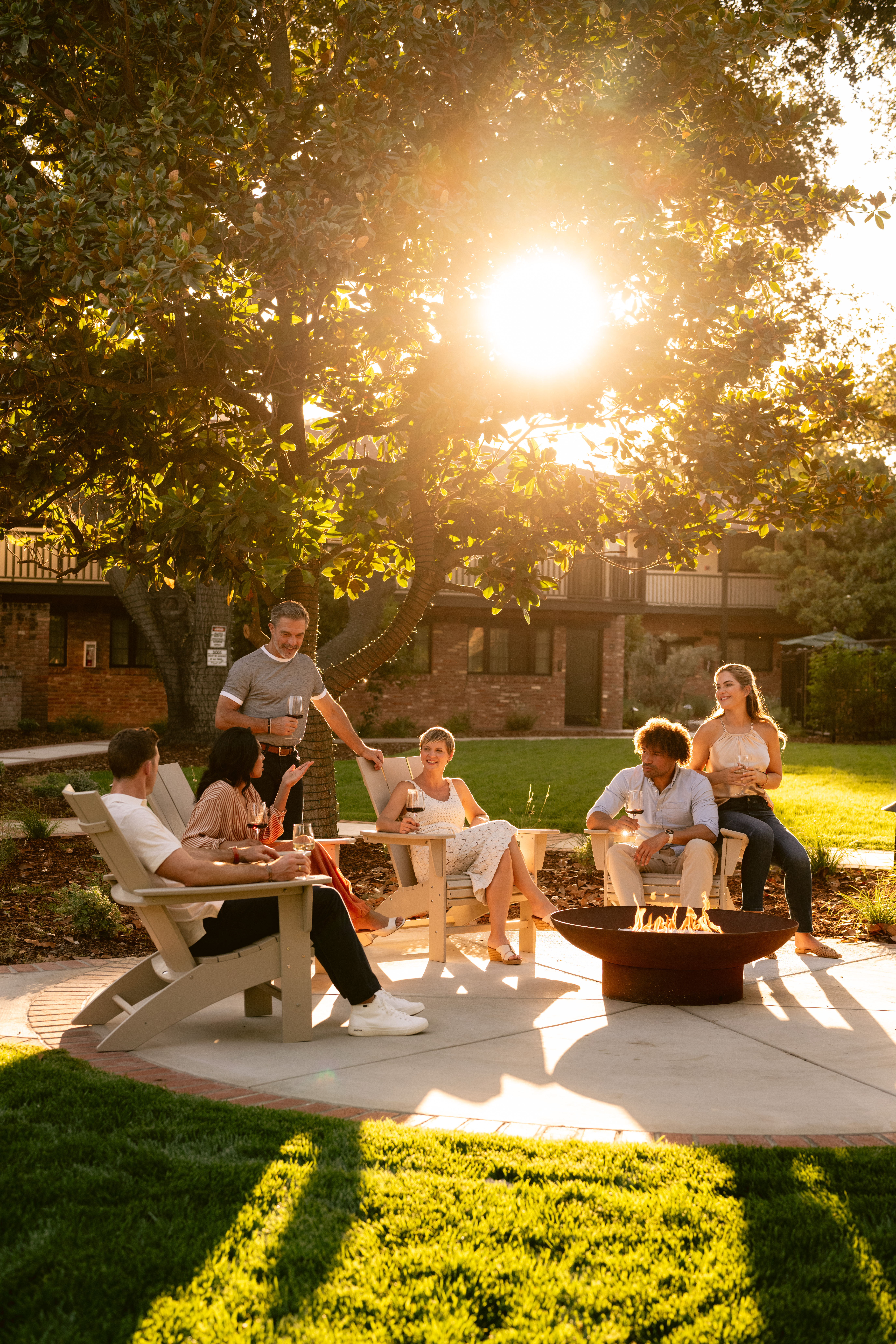 Group of friends relaxing and drinking wine by a garden fire pit at Paso Robles Inn.