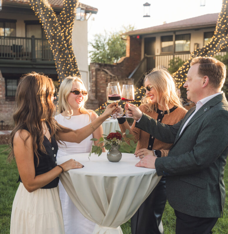 Group of friends gathered in a garden drinking wine.